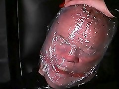 Mistress Aradia gets her latex slave ball-gagged and wraps his head with see-through shrink
