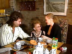 रसोई घर की मेज पर एक भरी हुई मुर्गा साझा करने दो तेजस्वी जर्मन लड़कियों