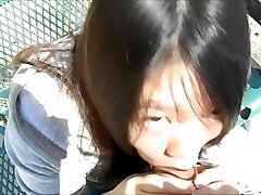 Asian woman deepthroating guys in the park in broad day light