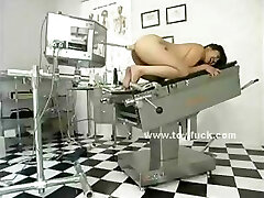Brunette naked on the medic table with legs spread wide is prepared for toy penetrations
