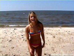 Hula hooping bombshell on the beach in a colorful bikini
