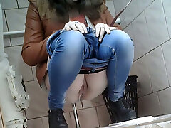 Slim girl in very tight blue denim filmed in the toilet room