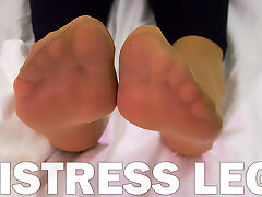 Mistress feet in delicate nylon socks is resting on the bed