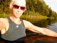 شنا کردن در دریاچه با لباس ورزشی در غروب آفتاب. شلوار و تی شرت خیس