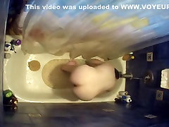 Nude woman bending over in bathtub