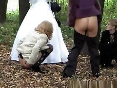 Three ladies help bride pee outdoors