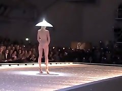 Seductive fashion model in a perverted mature hat walks down the catwalk in the nude