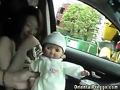 Pregnant asian breast feeds doll in car