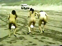 mujeres desnudas corren a través de la playa con una pelota entre sus