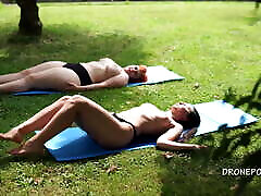 Two young petite crying girls sunbathing in the city park