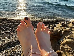 Mistress Lara plays with her japanese agents and toes on the beach