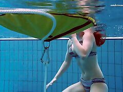 Cute redhead babe strips out of her bikini in the pool