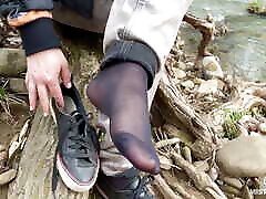 jeans taquinant les pieds dans la forêt en chaussettes en nylon