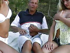 Two beautiful German chicks sharing a hard cock outdoors